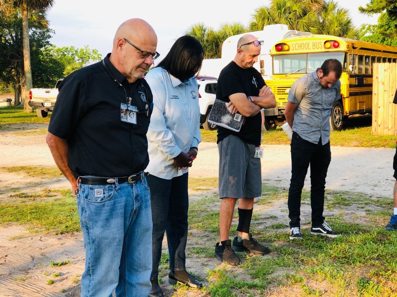 CITA Rescue Mission staff and volunteers praying together before outreach, with the ministry bus behind them in Melbourne, Florida.