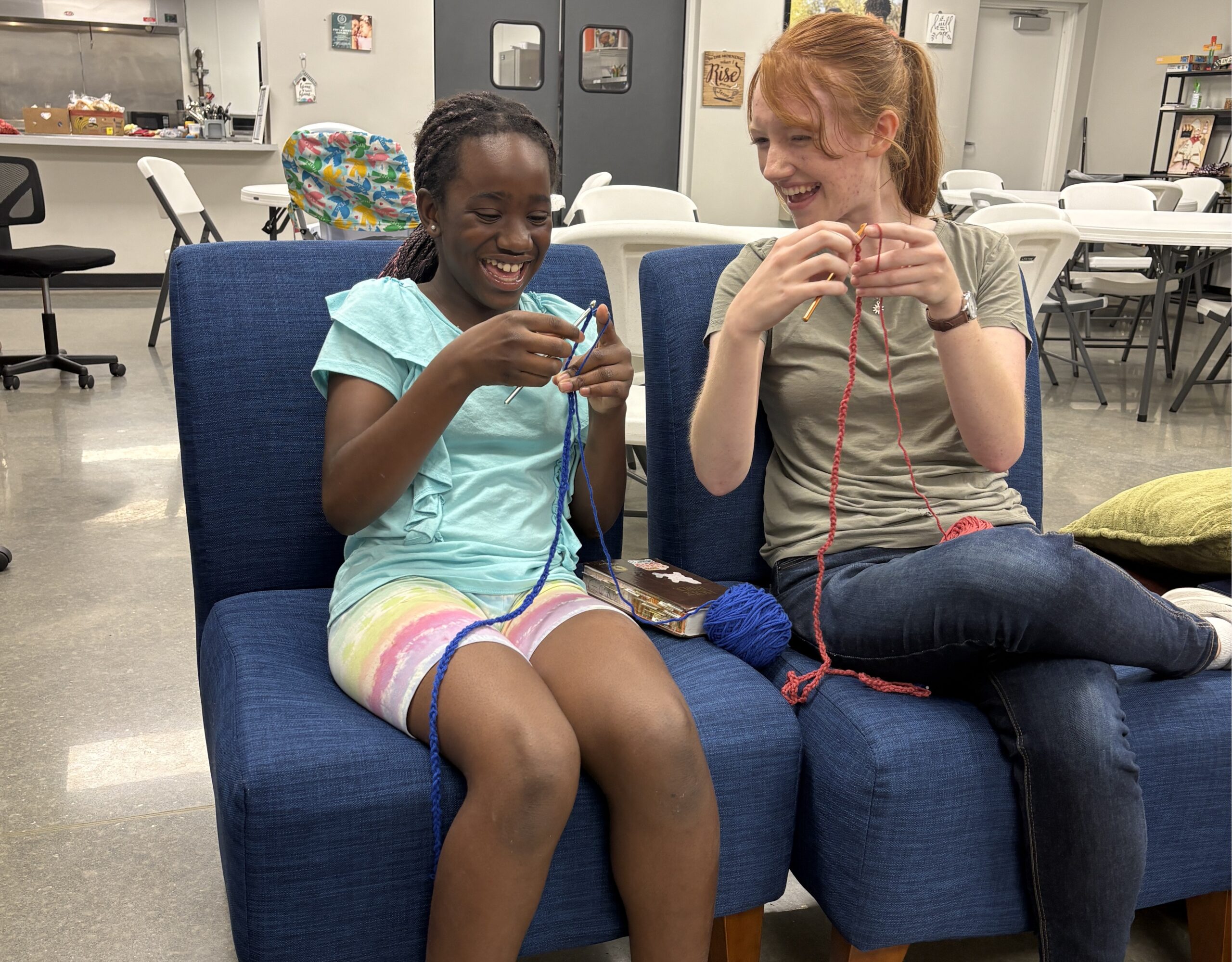 A volunteer spending time with a child at Helen's House through Bible study and crocheting