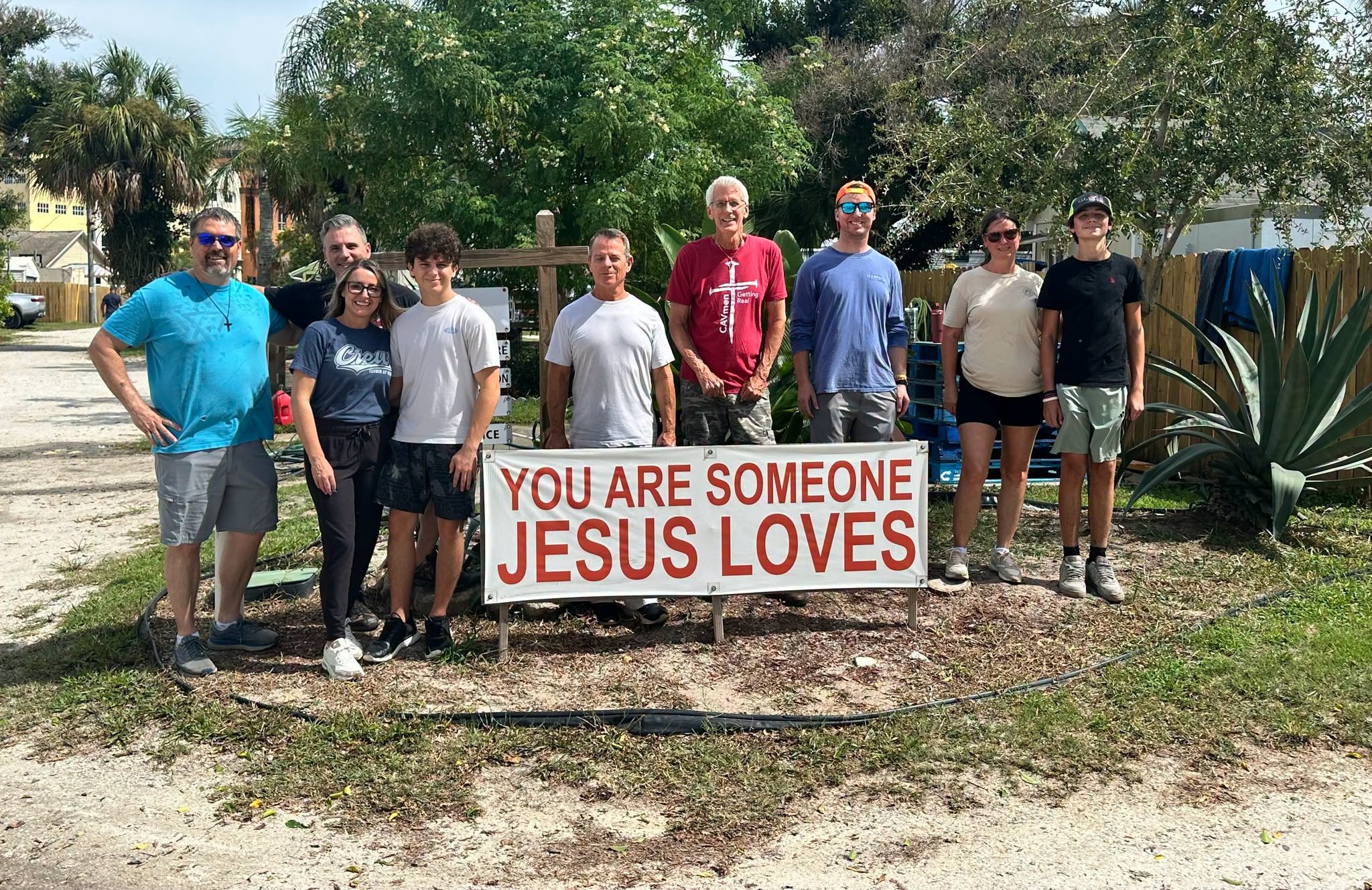 Church at Viera volunteers beside the You Are Someone Jesus Loves sign at Christ Is The Answer Rescue Mission